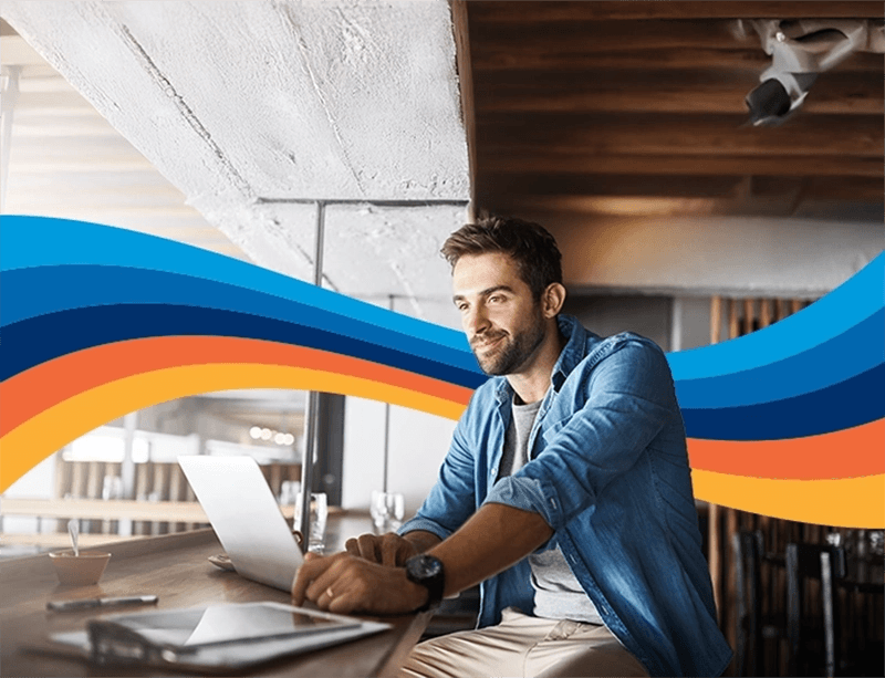 a man is sitting at a table using a laptop