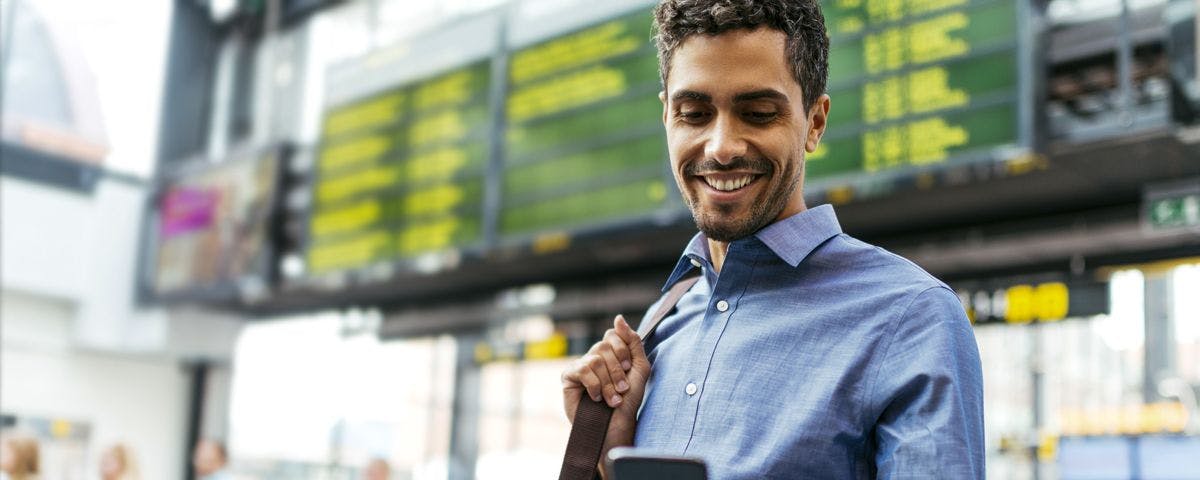 Man in train station holding phone