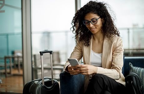 woman sitting looking at phone with luggage