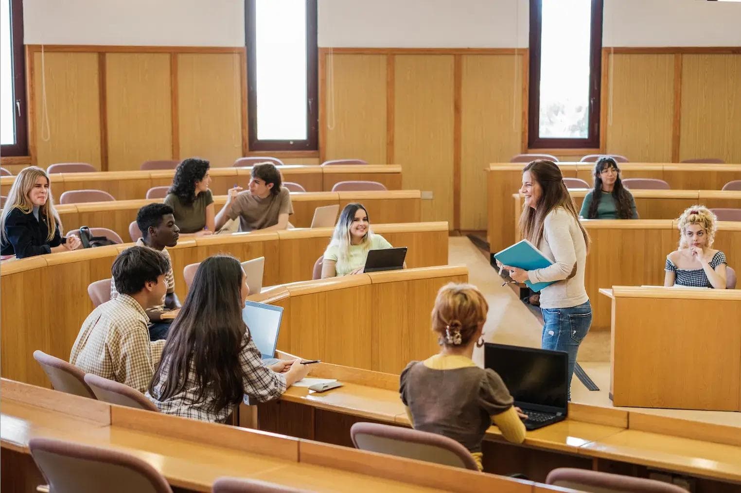 a group of students are sitting at desks in a lecture hall .