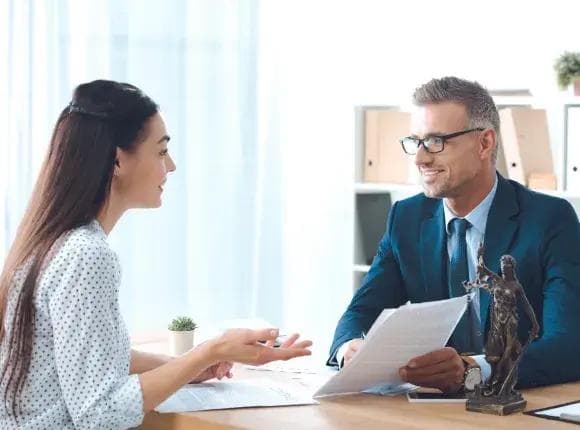 a man in a suit and tie is sitting at a desk talking to a woman .