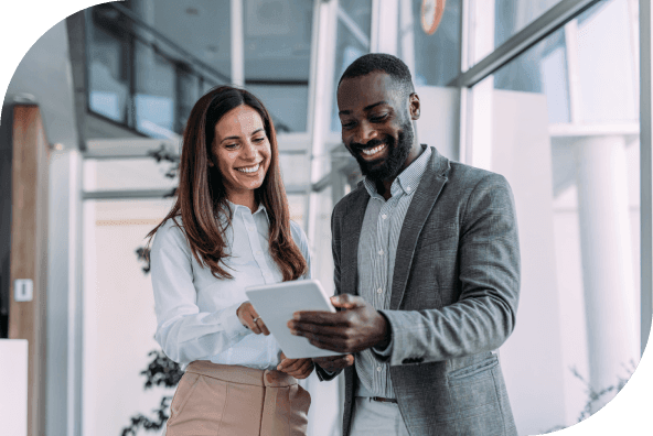 Two smiling business professionals looking at a tablet.
