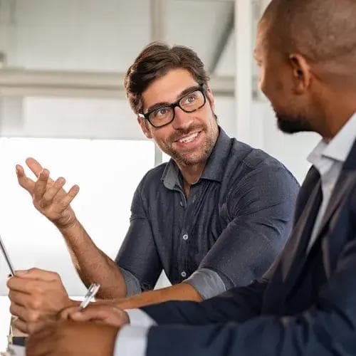 two lawyers are sitting at a table talking to each other .