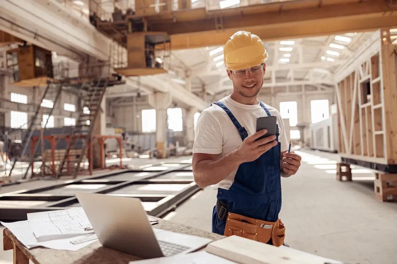 a construction worker is using a cell phone in a factory .